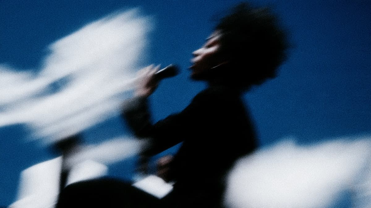 A singer with a microphone, blurred, against blue sky