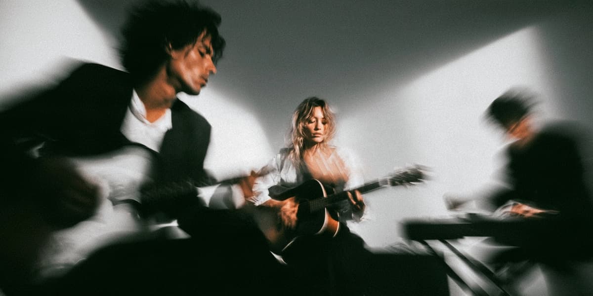 A band with acoustic guitars and keys in a white room